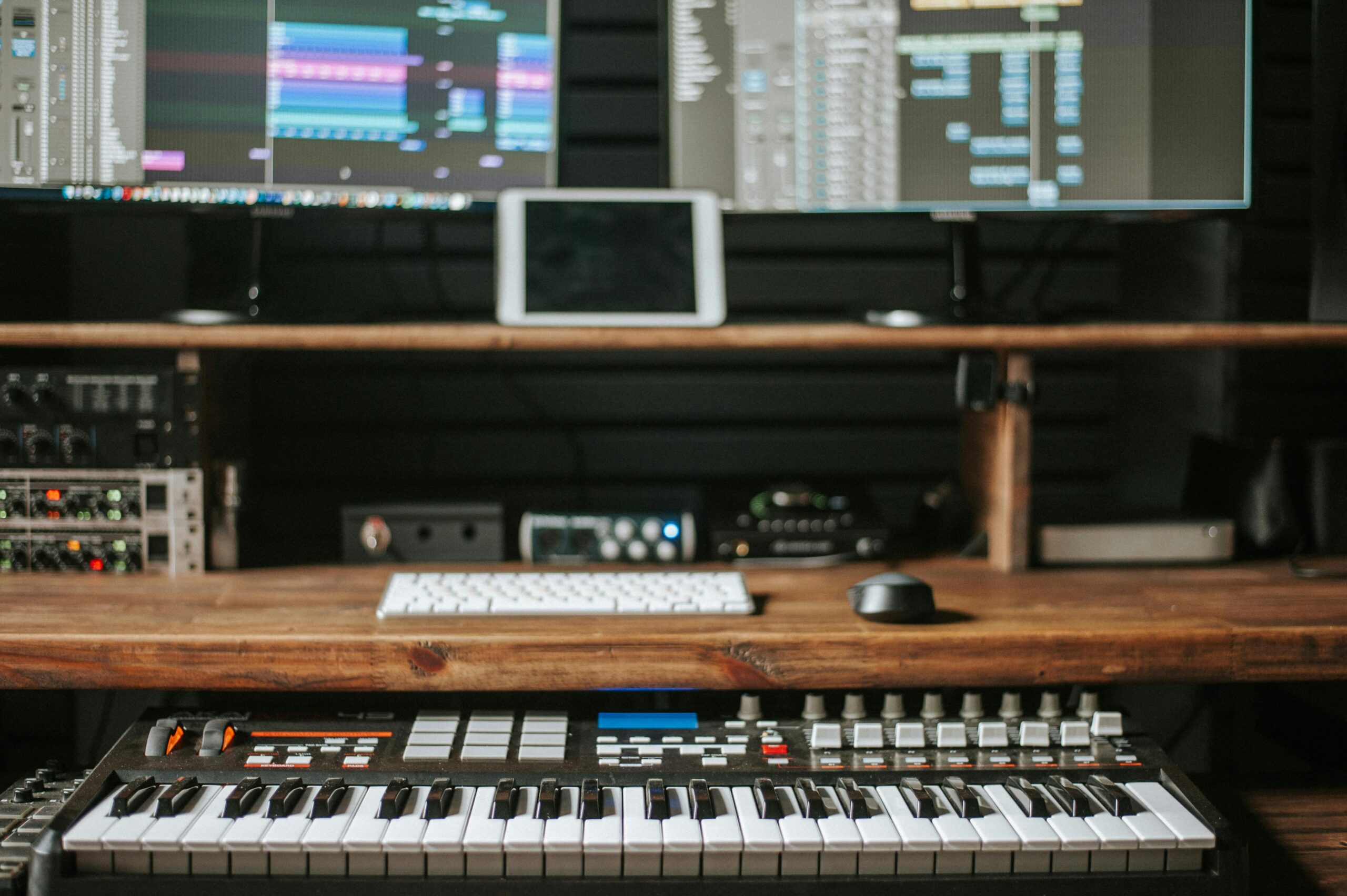 Home Professional music production setup featuring keyboard, computer screens, and audio equipment.