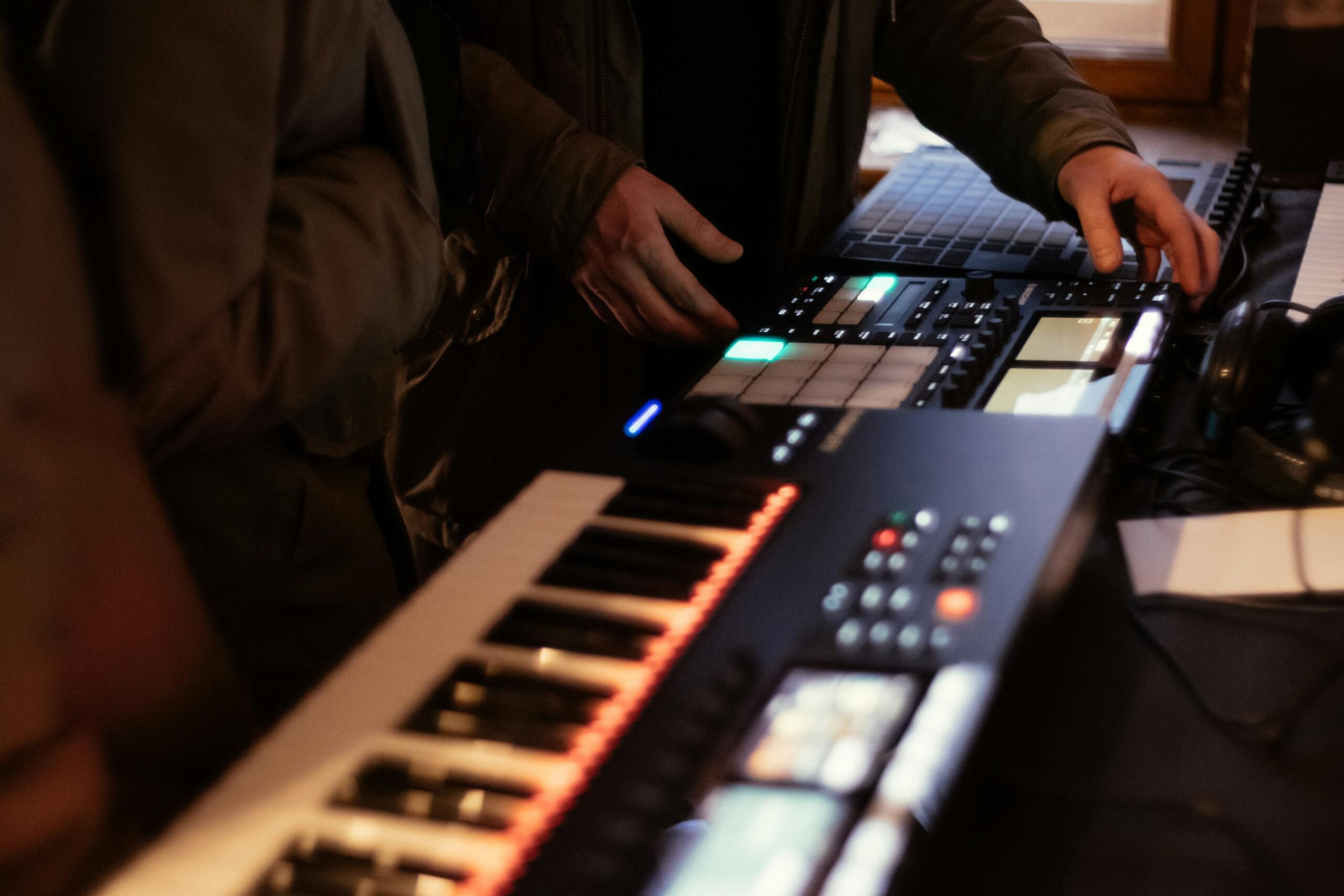 Home Music producer using synthesizer and beat pad in studio setting.