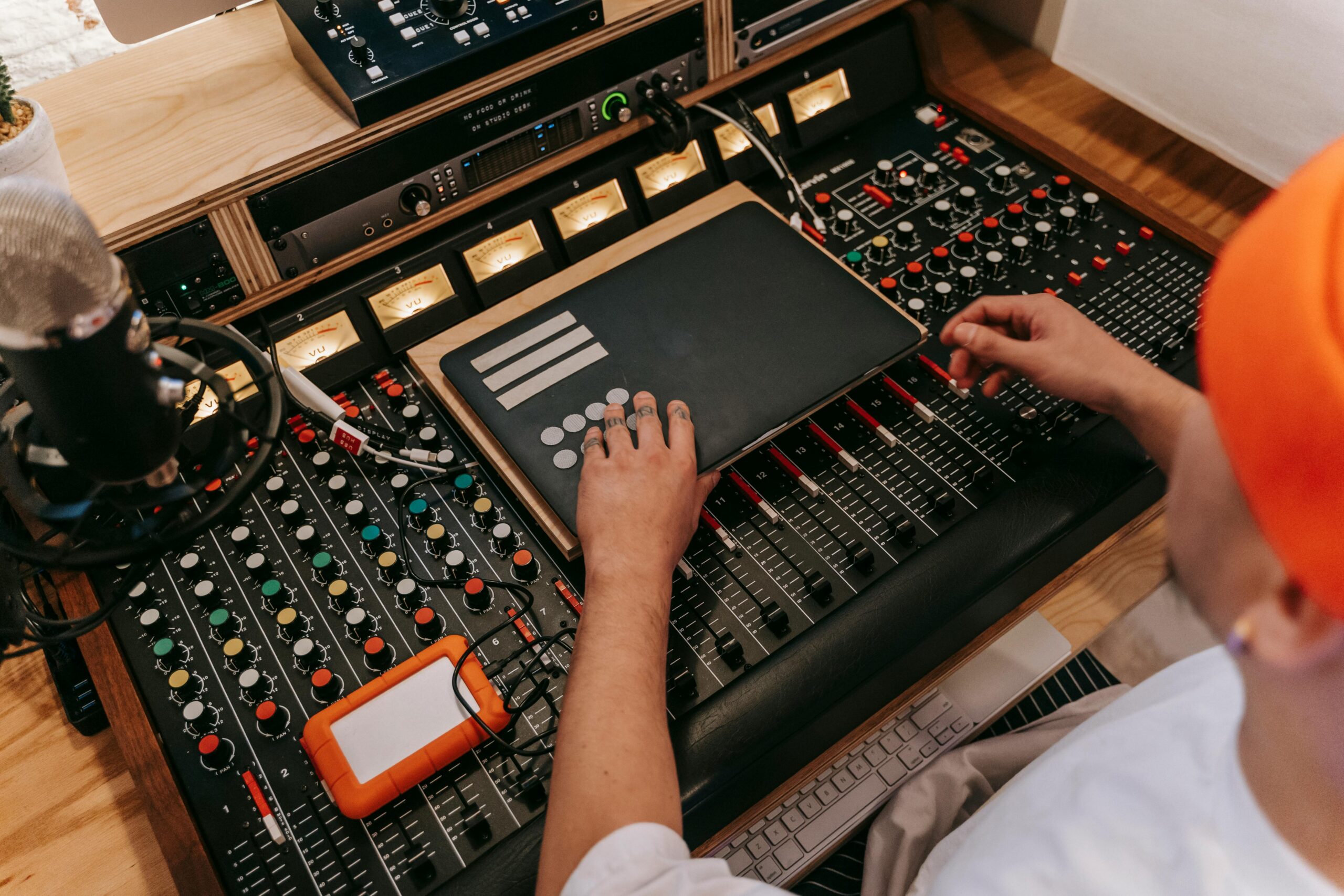 Home High angle view of a DJ using sound mixer and technology equipment in a studio setting.